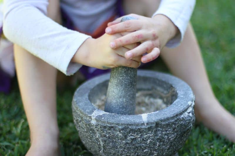 Child using a mortar and pestle in the garden
