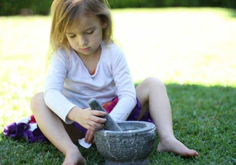 Child using a mortar and pestle in the garden